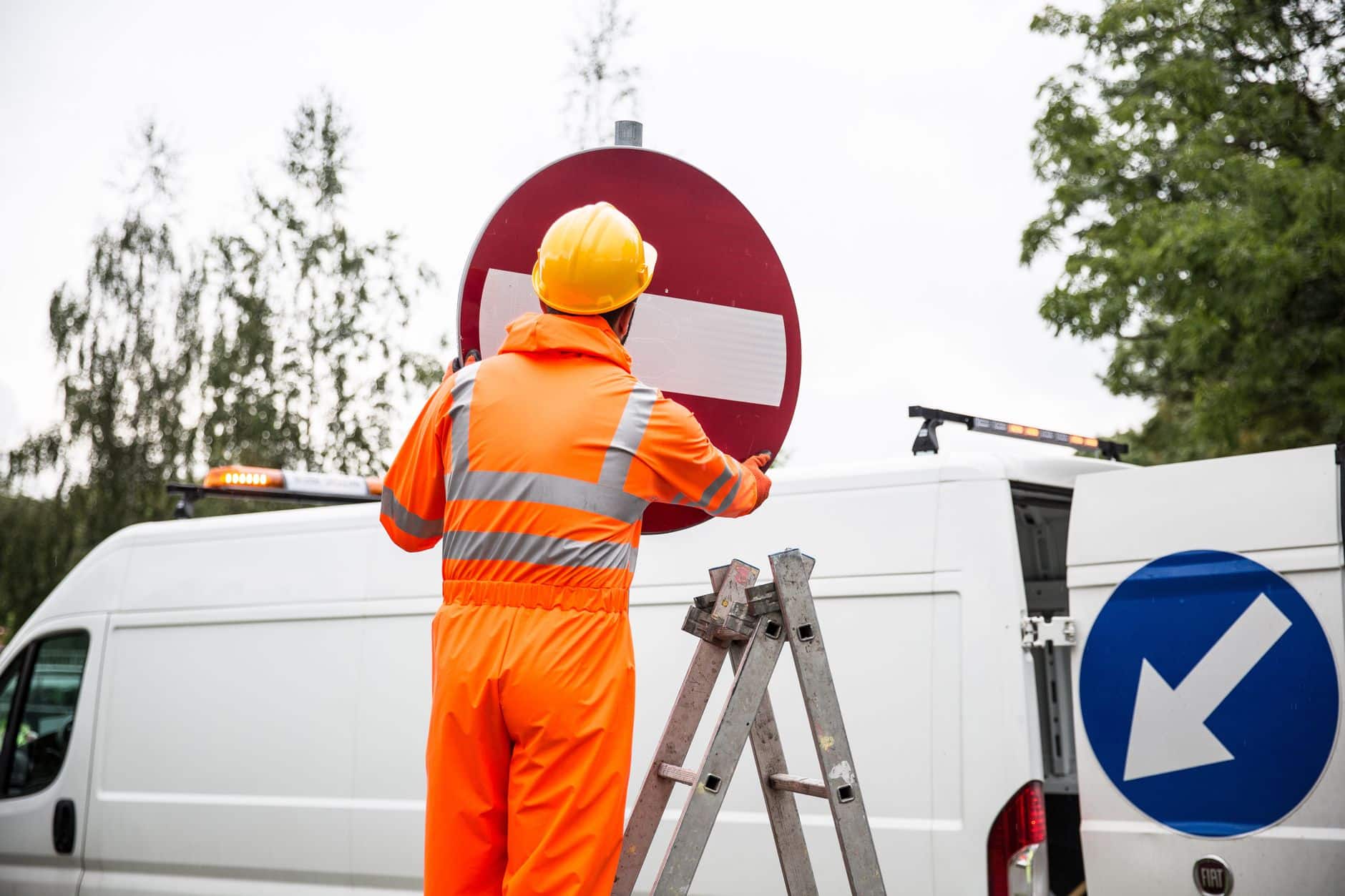 A technician installing outdoor business signs on a building exterior