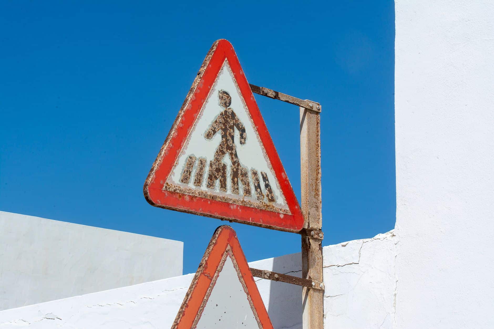 A faded and weathered outdoor sign board showing sun damage over time